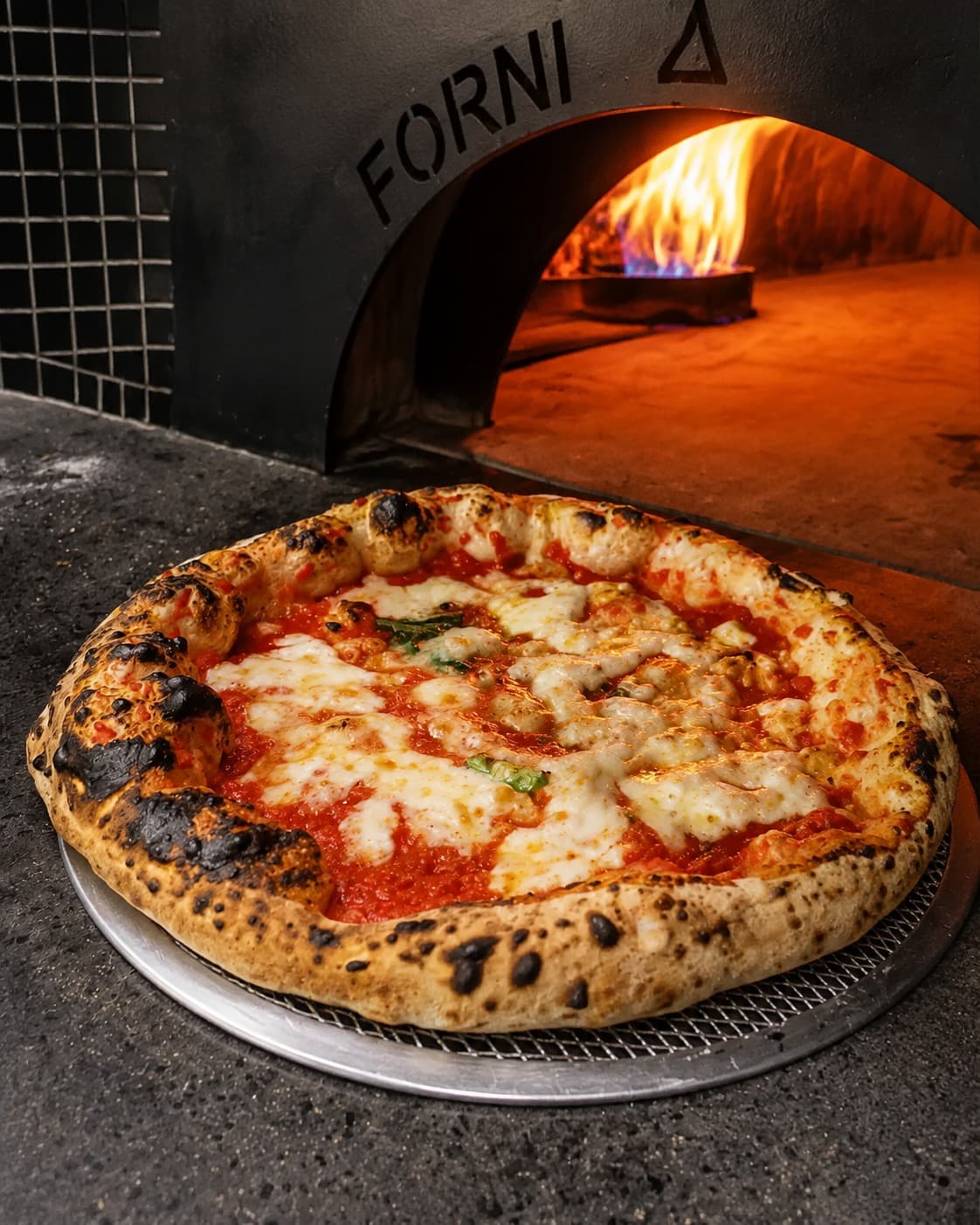 Pizza appena sfornata davanti al forno a legna